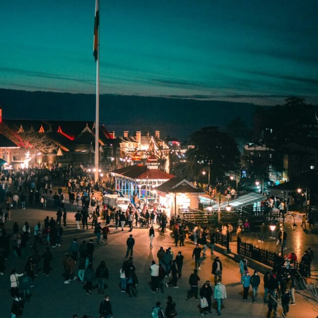 a crowd of people standing around a carnival at night in Shimla